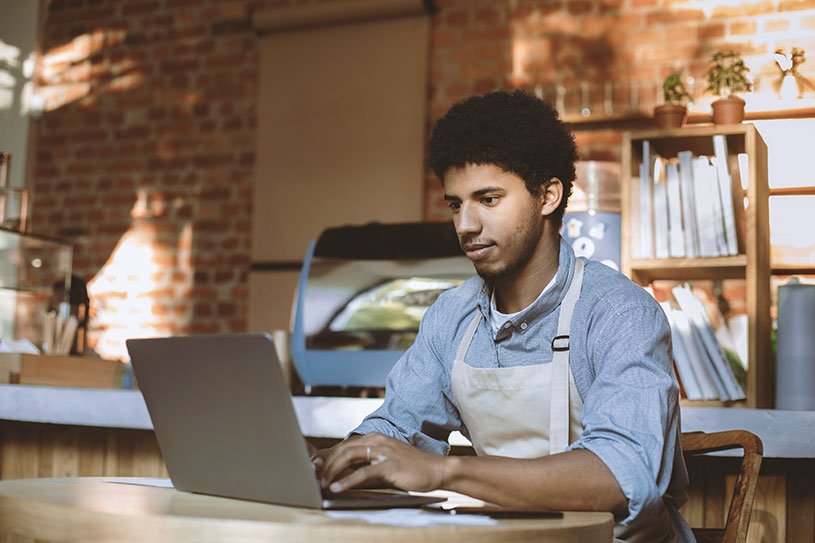 Man in a café typing on a laptop